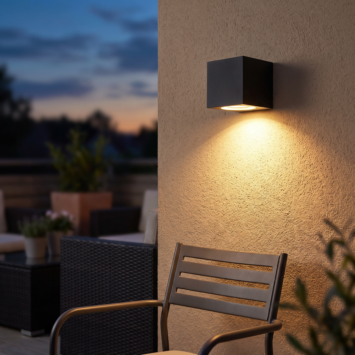 Zwarte buitenwandlamp op een tuinmuur bij een terras