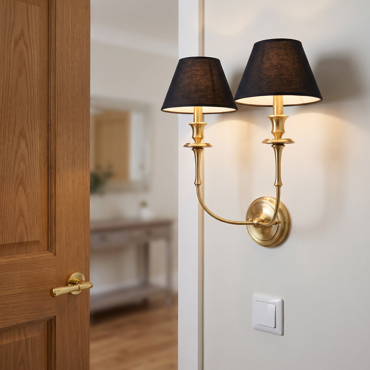 Messing wandlamp met zwarte stoffen kap in hal naast messing deurklink