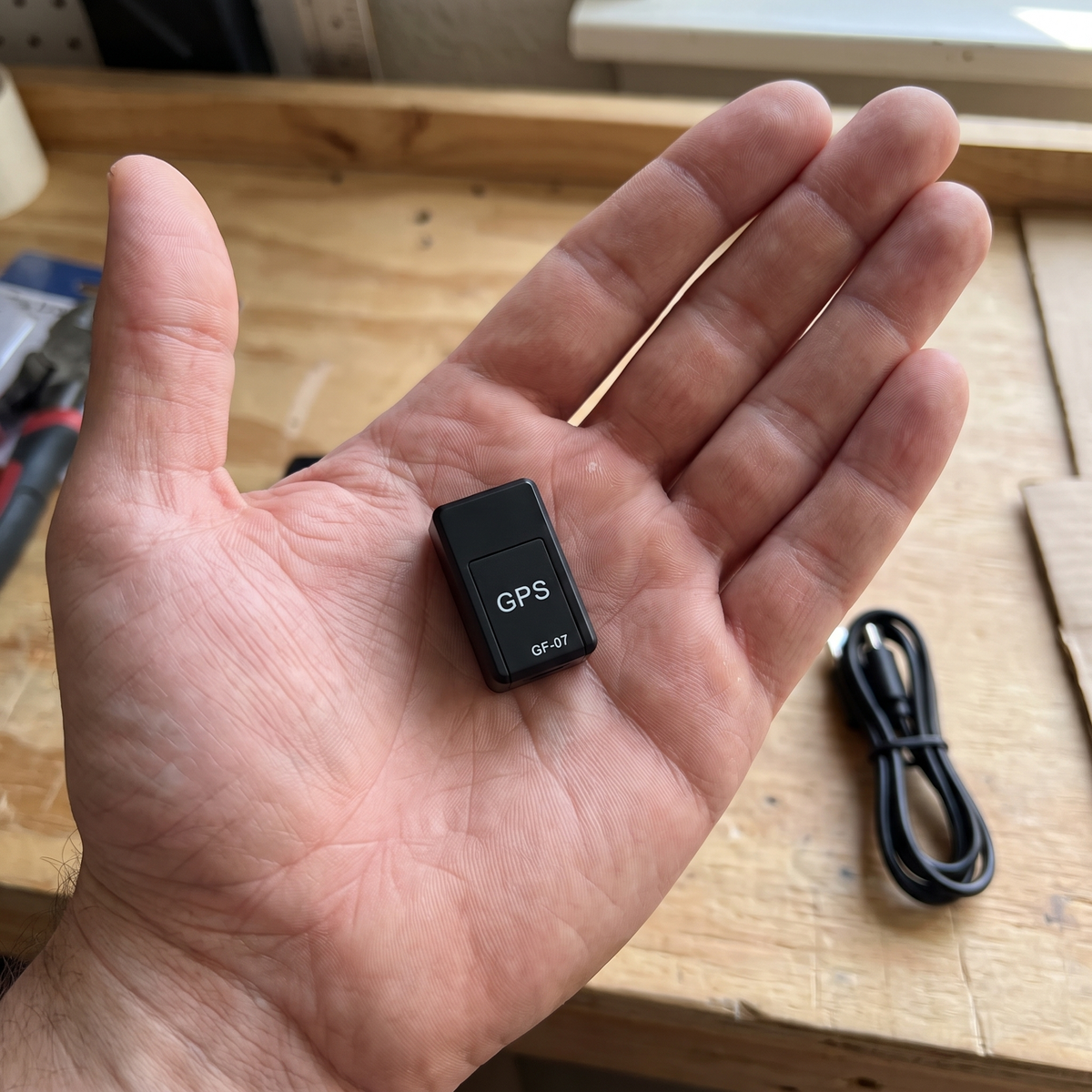 GPS tracker in een open hand op een werkbank